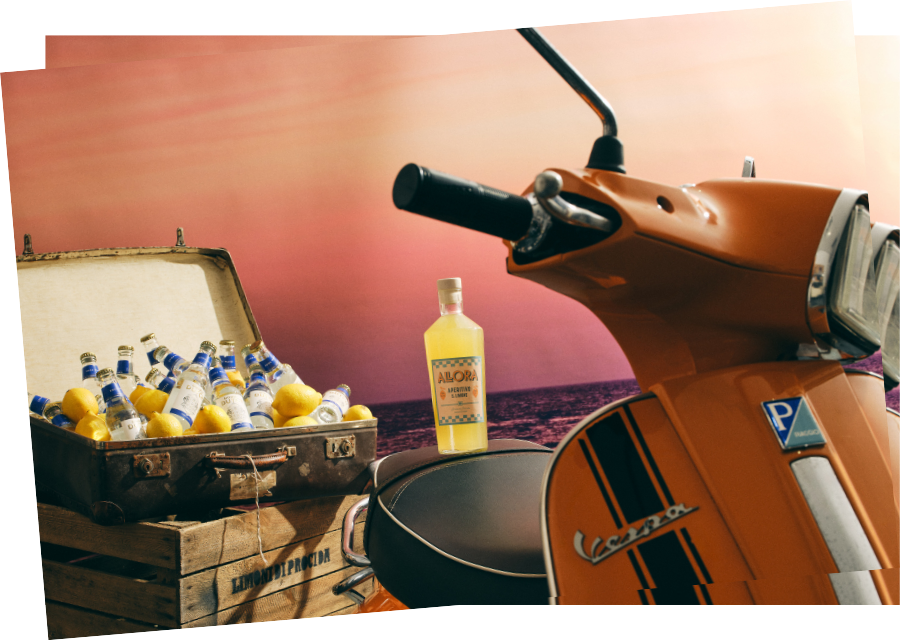 Horizontal postcard with a suitcase filled with glass water bottles and lemons next to an orange moped with an Allora bottle on its seat